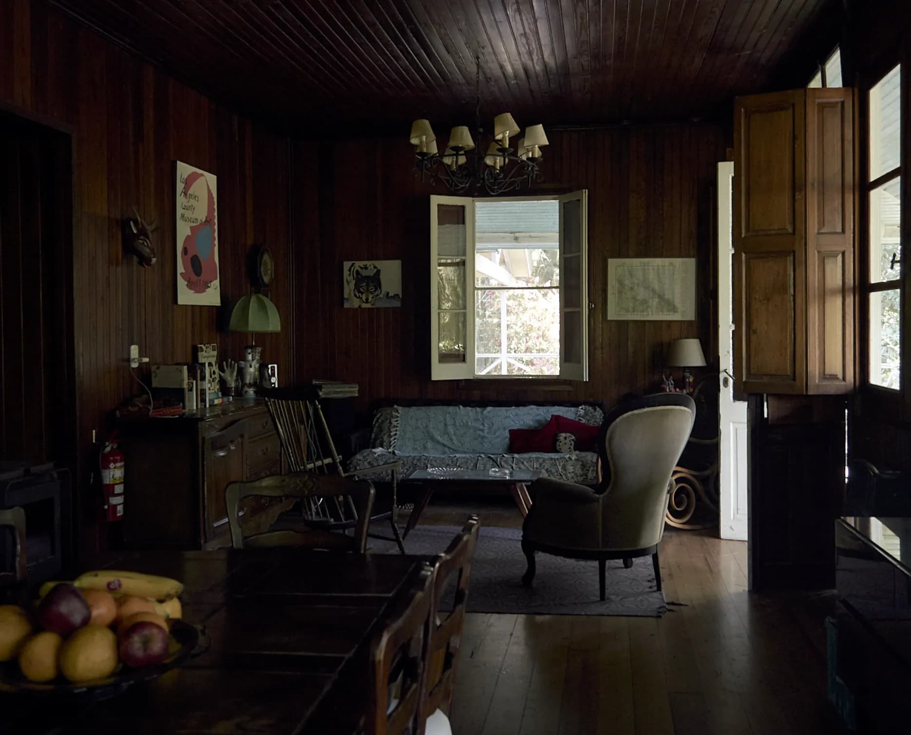 Living de una casa de madera con sillones y una ventana al jardín