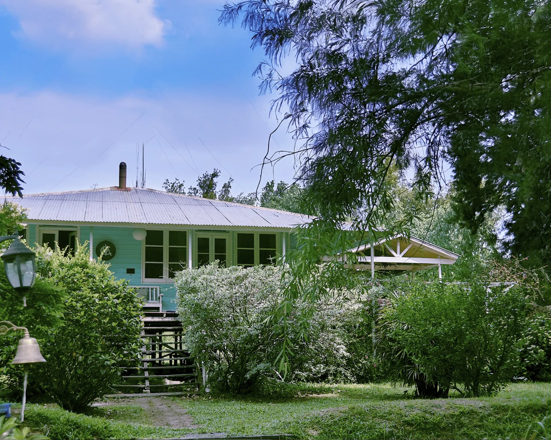 Una casa isleña pintada de verde agua entre árboles y jardín