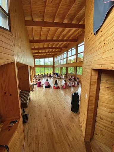Un grupo sentado en ronda en un salón de madera con grandes ventanales